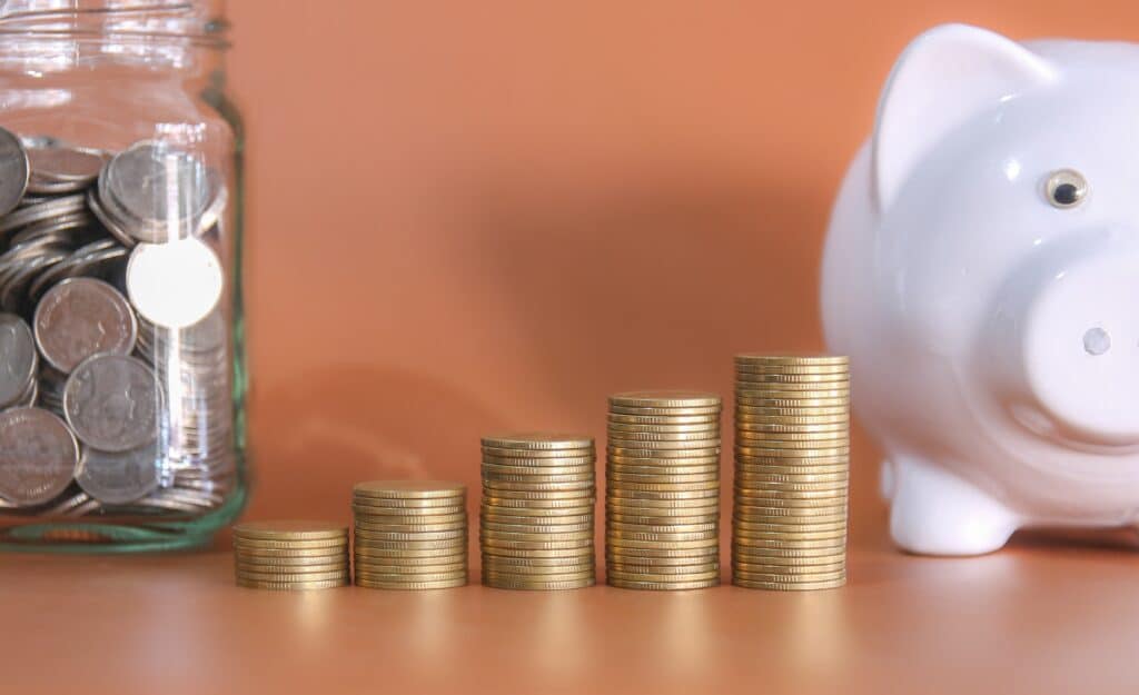 Coins stacked up with a piggy bank.